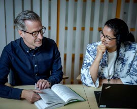 En man och en kvinna sitter och samtalar vid en laptop.