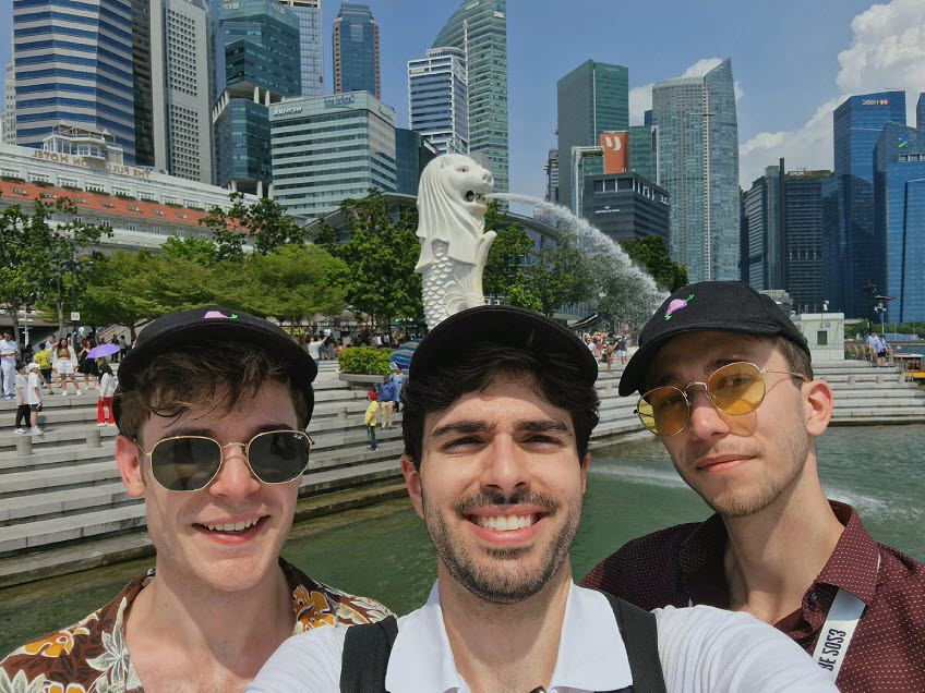 Tre killar tar en selfie framför en fiskstaty i Singapore.