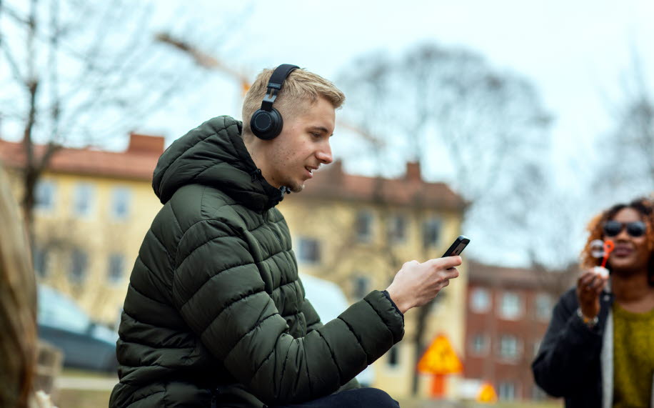 Man sitting outside with headphones and smartphone