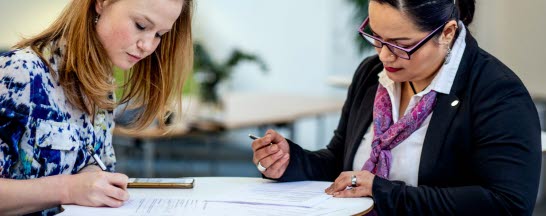 Two women signing papers.