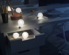 Glödlampor som ligger och lyser på ett skrivbord i ett nedsläckt kontor.