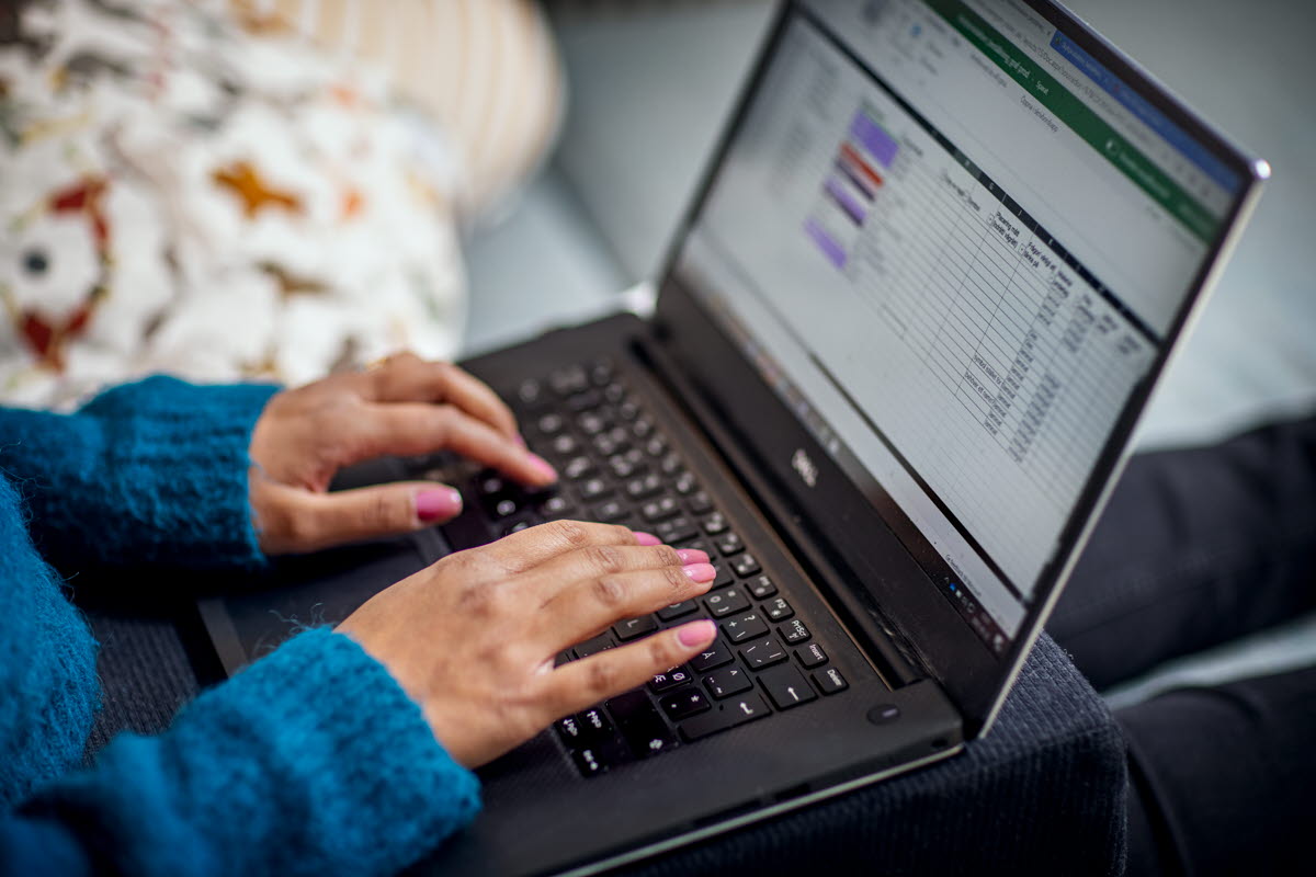 Kvinna sitter och skriver på en laptop.