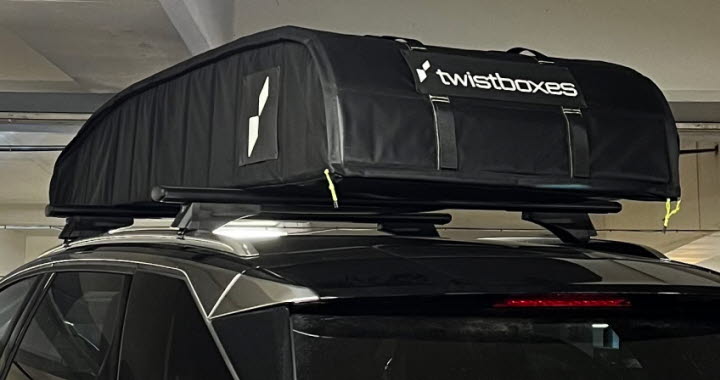 En svart takbox i kanvas med texten Twistboxes är monterad på en svart bil