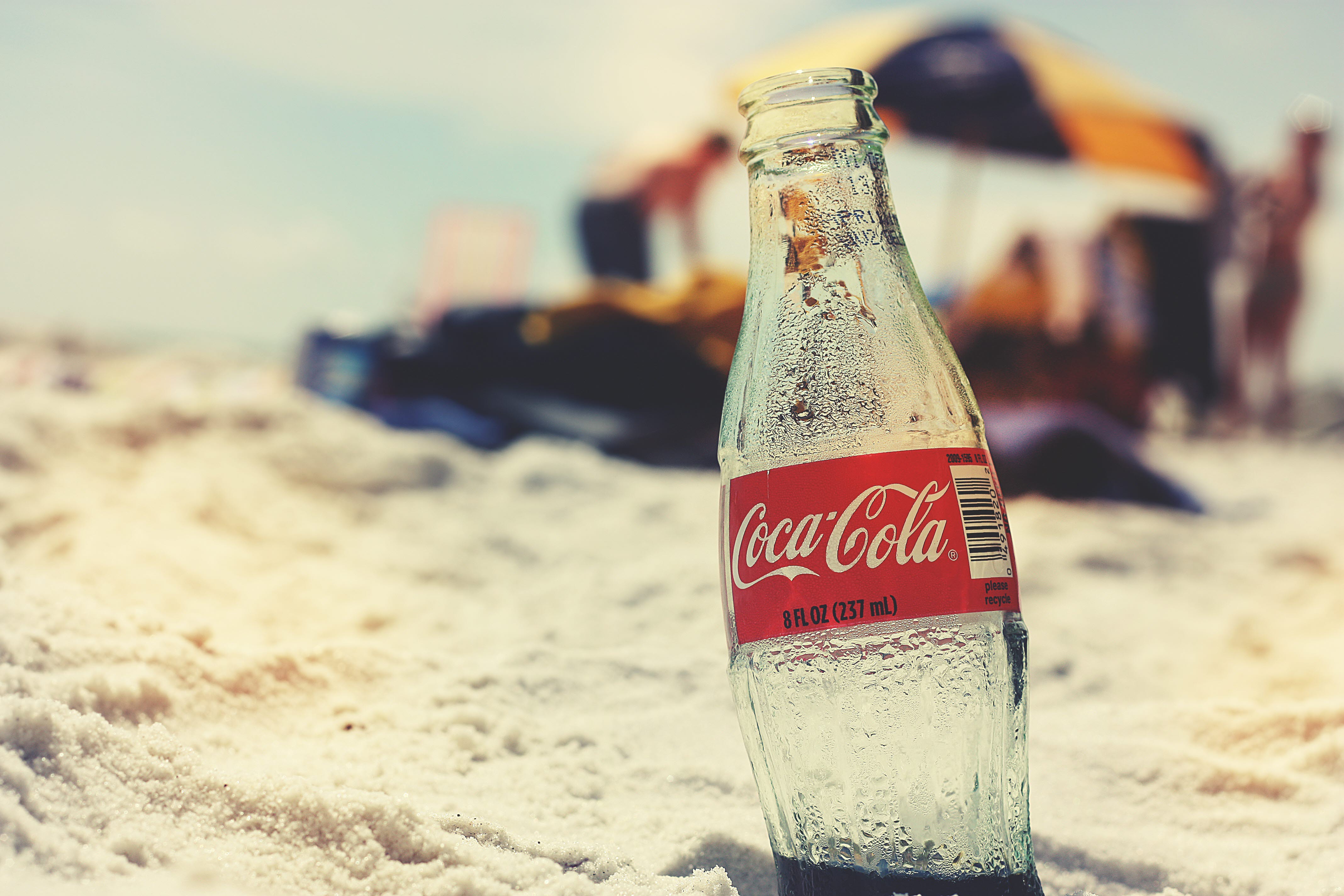En tom coca-cola flaska i sanden på en sandstrand