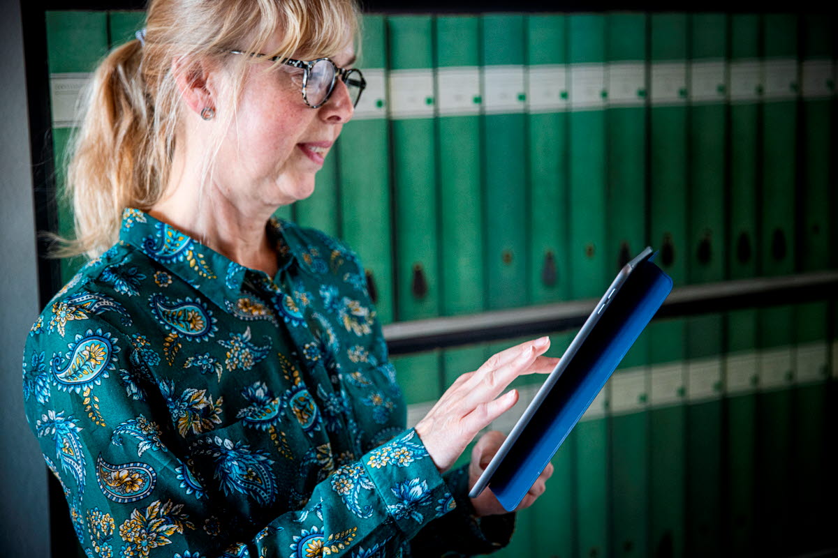 Woman reading on an iPad with green binders in the background.