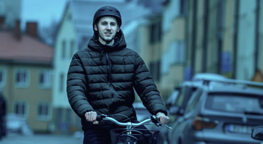 Kvinna i gul tröja sitter vid en dator med headset. 