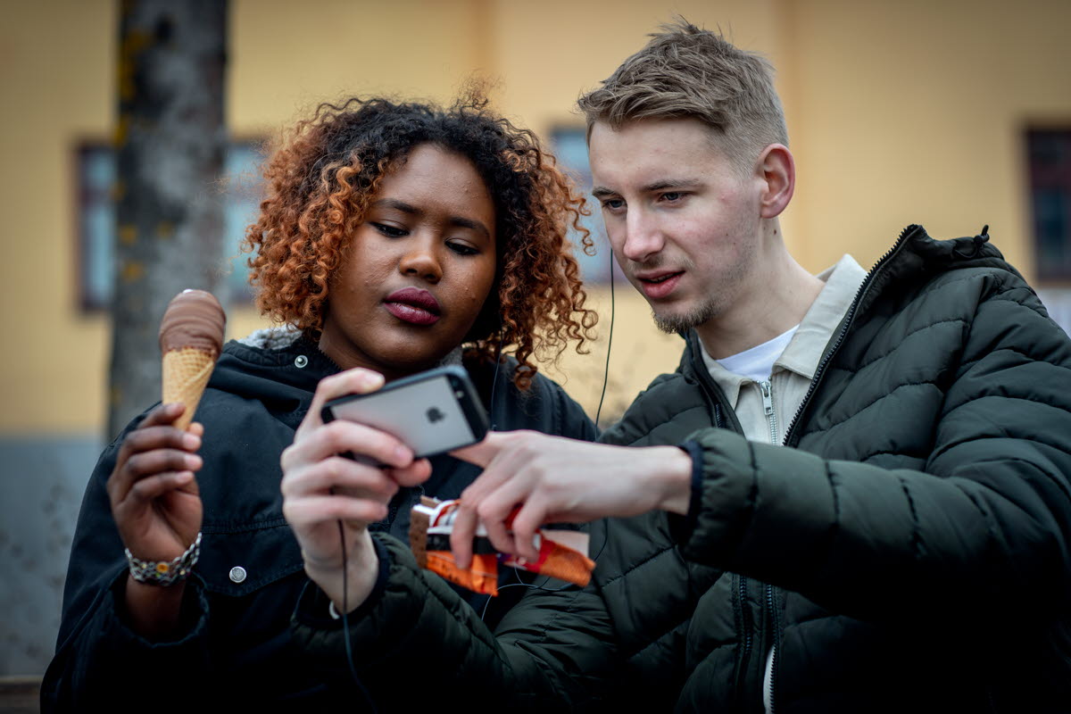 En kille och en tjej tittar på något på en mobiltelefon