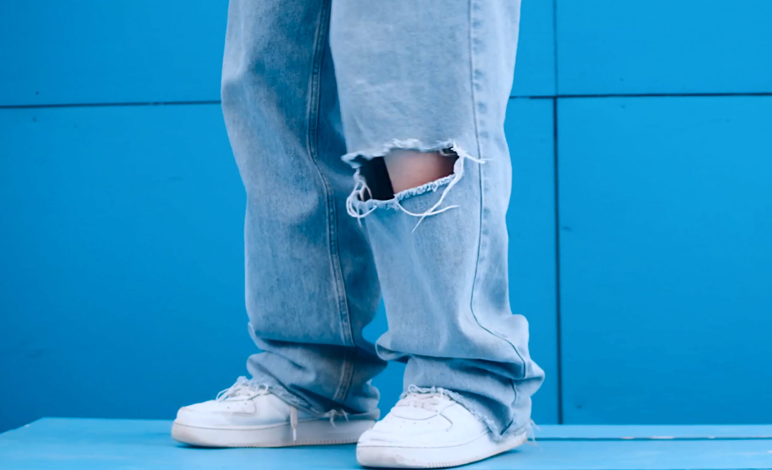 Unga ben i vita sneakers och pösiga jeans